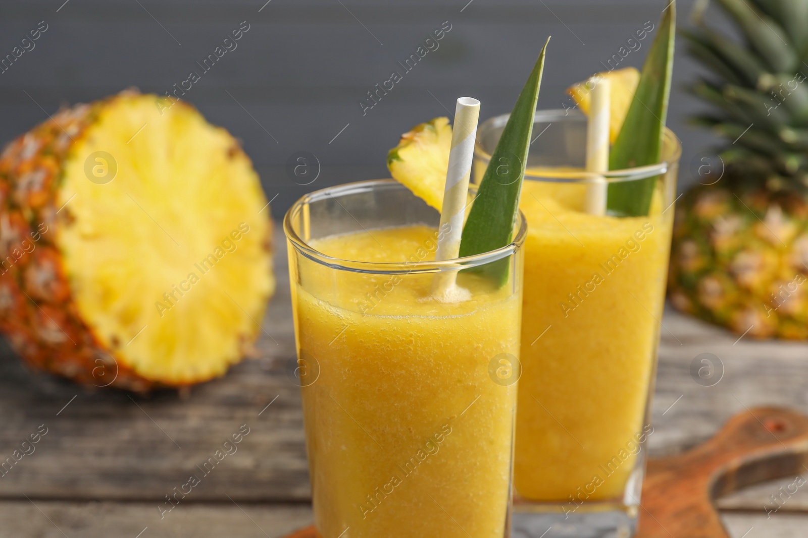 Photo of Tasty pineapple smoothie and cut fruit on table, closeup