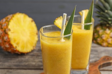 Tasty pineapple smoothie and cut fruit on table, closeup