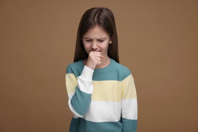 Photo of Sick girl coughing on brown background. Cold symptoms