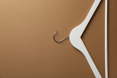 Photo of Empty white hanger on brown background, top view. Space for text