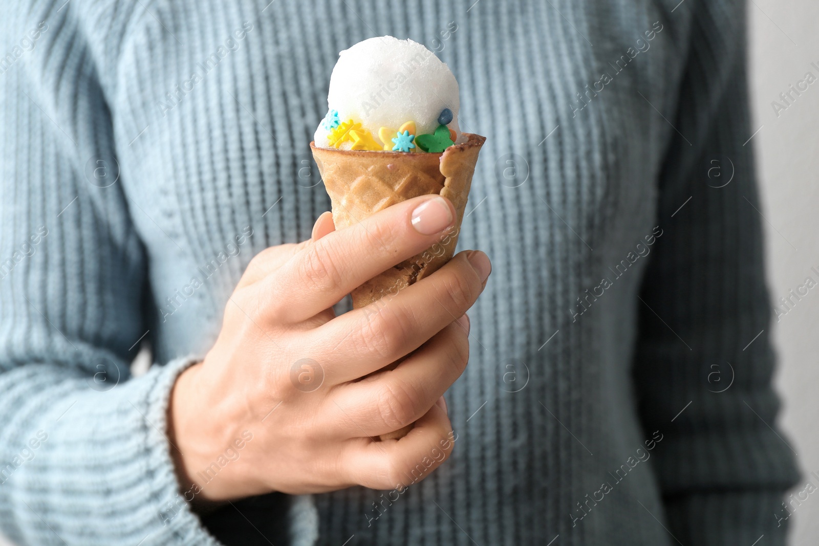 Photo of Woman with snow ice cream cone on light background, closeup