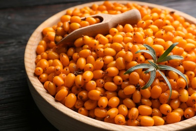 Photo of Ripe sea buckthorn berries on black wooden table, closeup