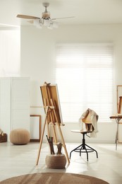Photo of Modern studio interior with artist's workplace and easel