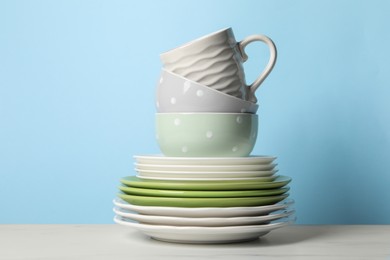 Photo of Beautiful ceramic dishware and cup on white marble table