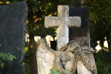 Photo of Beautiful statue of angel with cross at cemetery. Religious symbol