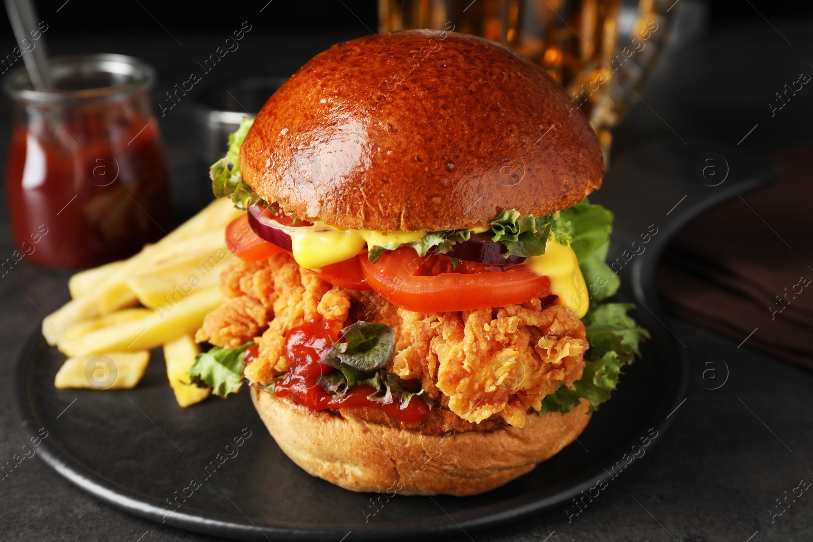 Photo of Delicious burger with crispy chicken patty and french fries on black table, closeup
