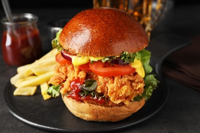 Photo of Delicious burger with crispy chicken patty and french fries on black table, closeup
