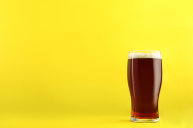 Photo of Delicious homemade kvass in glass on yellow background. Space for text