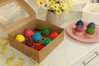 Delicious colorful cupcakes and beautiful flowers on white table