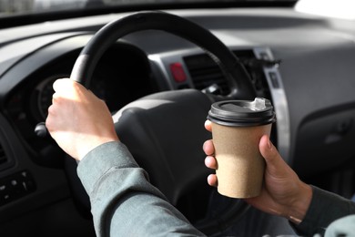 Photo of Coffee to go. Man with paper cup of drink driving his car, closeup