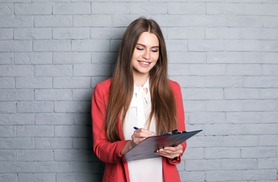 Photo of Beautiful real estate agent with clipboard on brick wall background