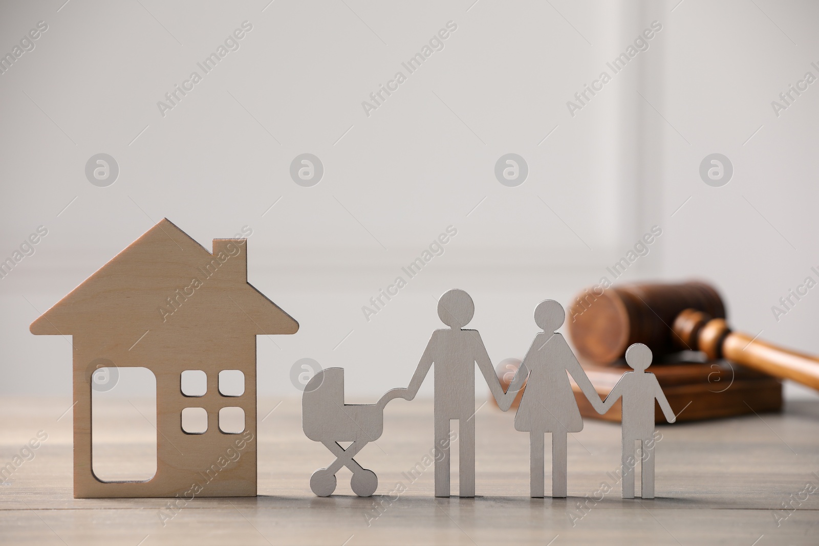 Photo of Family law. Figure of parents with children, house model and gavel on wooden table, space for text