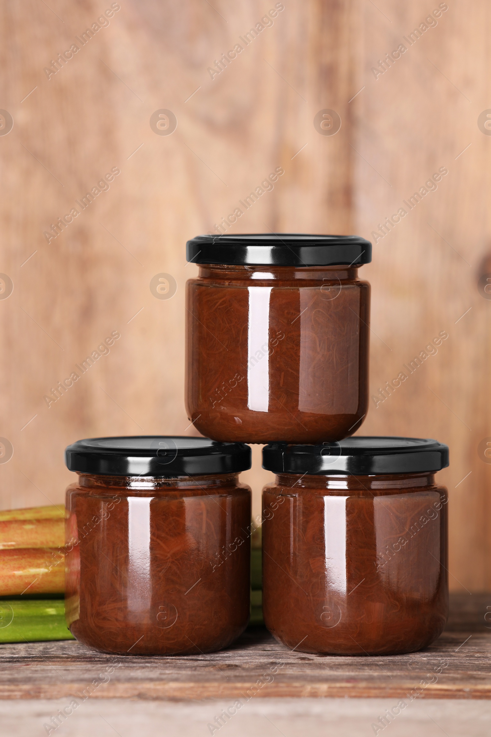 Photo of Jars of tasty rhubarb jam on wooden table