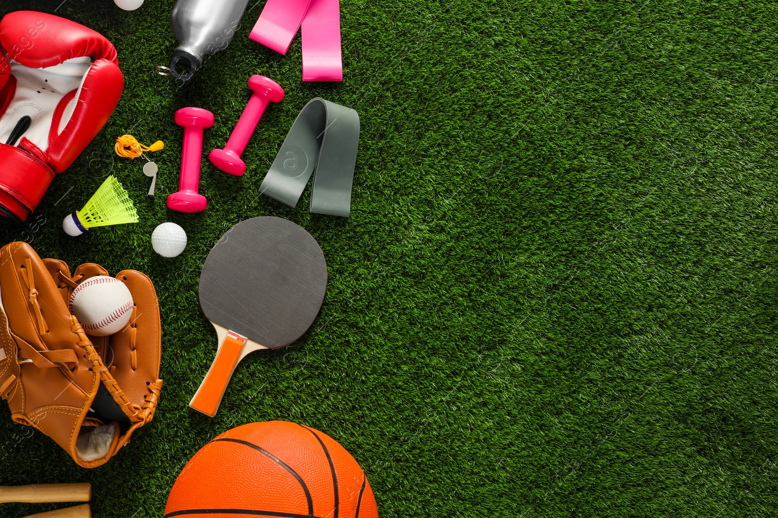 Photo of Different sport equipment on green grass, flat lay. Space for text