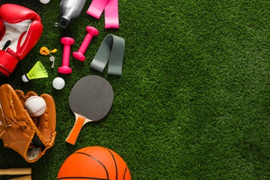 Photo of Different sport equipment on green grass, flat lay. Space for text