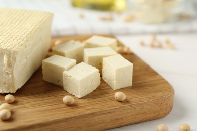 Photo of Cut tofu and soya beans on white wooden table, closeup