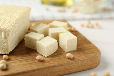 Cut tofu and soya beans on white wooden table, closeup