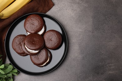 Photo of Tasty sweet choco pies, bananas and mint on brown table, flat lay. Space for text