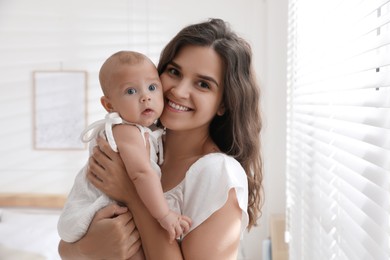 Photo of Happy young mother with her cute baby near window at home