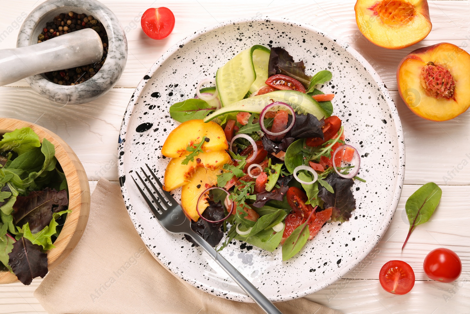 Photo of Delicious salad with vegetables and peach served on white wooden table, flat lay