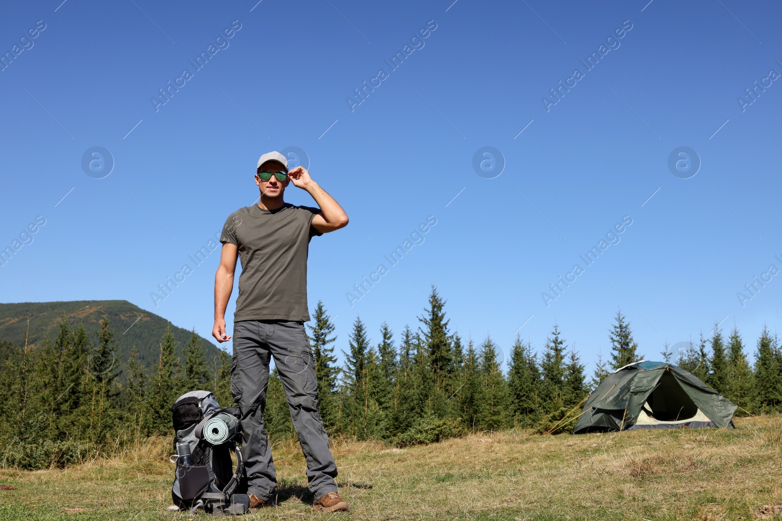 Photo of Tourist with backpack in mountains on sunny day. Space for text