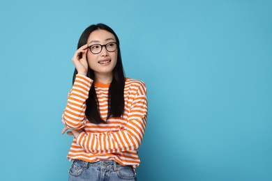 Portrait of happy woman in glasses on light blue background. Space for text