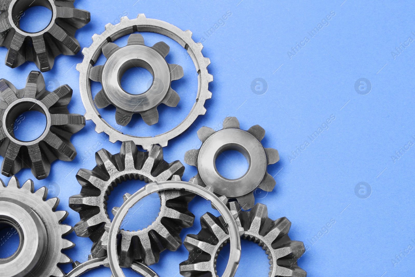 Photo of Different stainless steel gears on light blue background, flat lay. Space for text