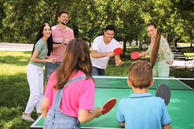 Photo of Happy family with children playing ping pong in park