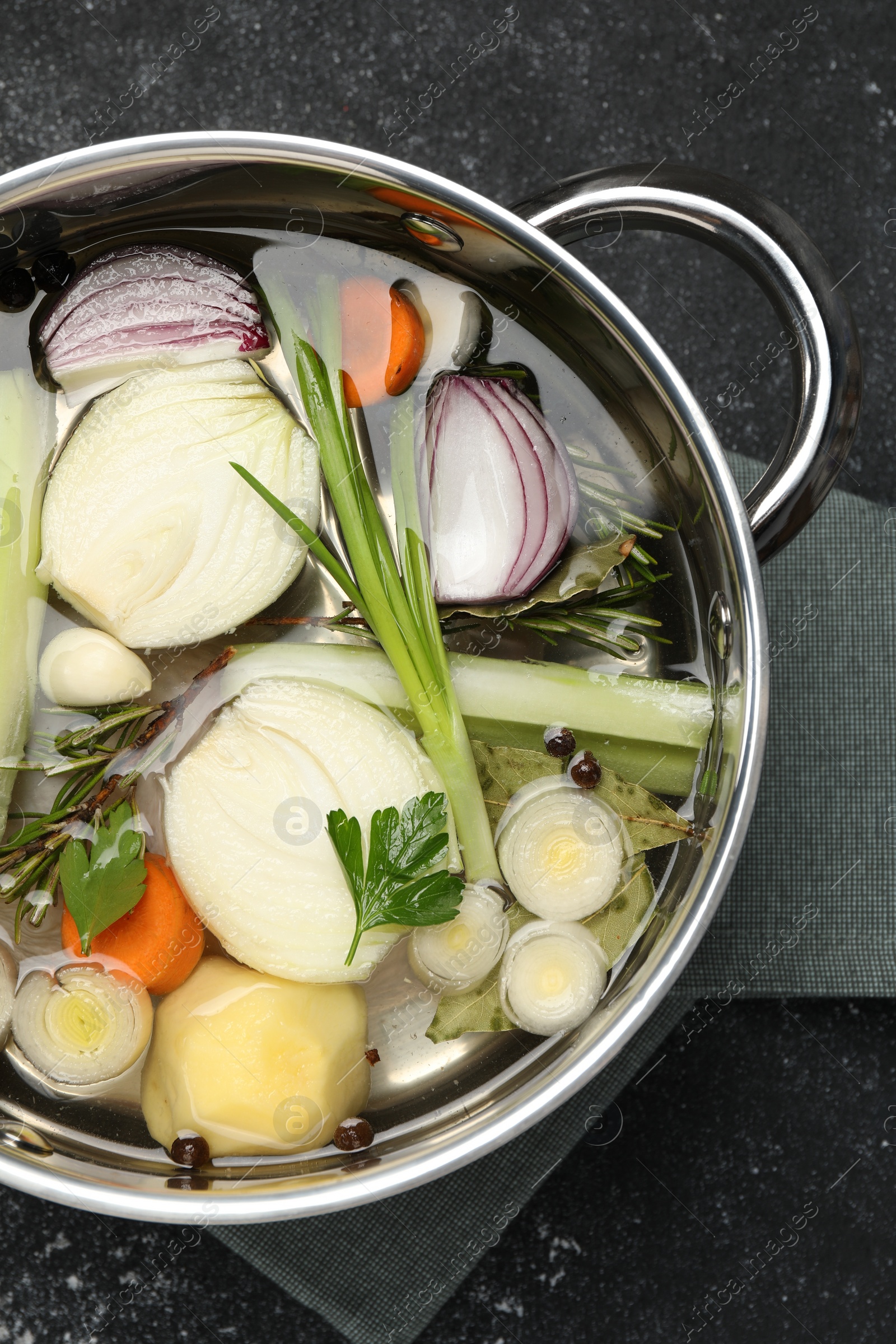 Photo of Different ingredients for cooking tasty bouillon in pot on black table, top view