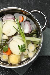 Different ingredients for cooking tasty bouillon in pot on black table, top view