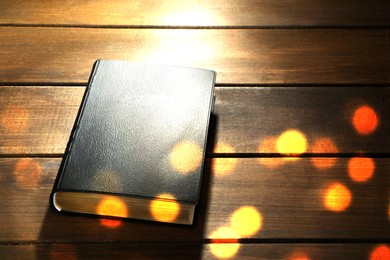 Closed Bible on wooden table, bokeh effect