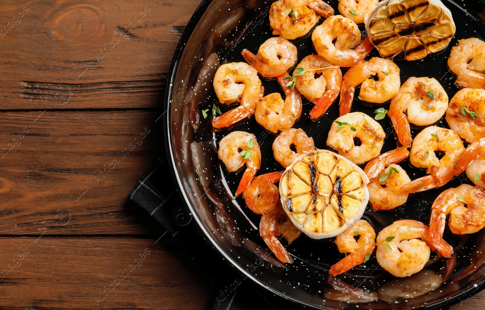 Photo of Frying pan with delicious shrimps on wooden background, top view