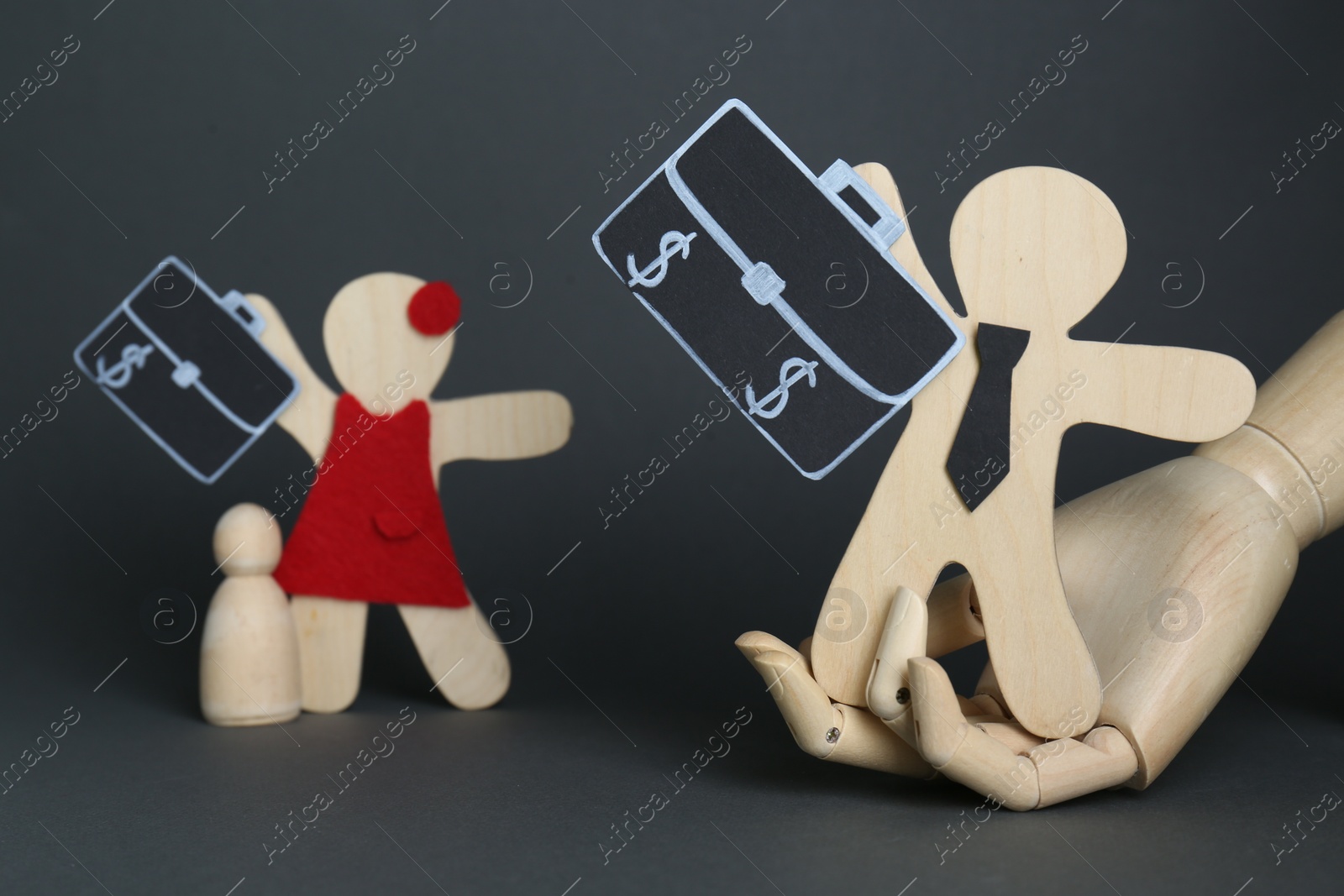 Photo of Gender pay gap. Wooden mannequin hand, figures of man and woman on black background