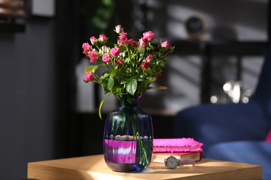 Photo of Glass vase with fresh flowers and wristwatch on wooden table