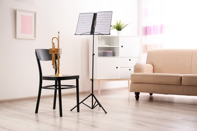 Photo of Trumpet, chair and note stand with music sheets in room
