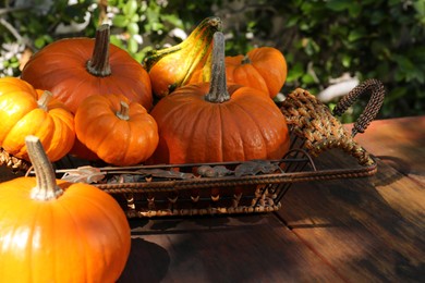 Many ripe orange pumpkins on wooden table outdoors