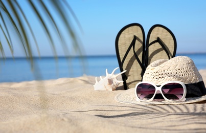 Photo of Stylish beach accessories on sand near sea