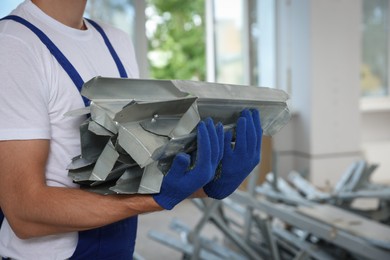 Construction worker with used building materials in room prepared for renovation, closeup