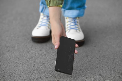 Photo of Woman taking dropped smartphone from asphalt, closeup. Device repairing