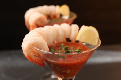 Photo of Tasty shrimp cocktail with sauce in glasses on blurred background, closeup