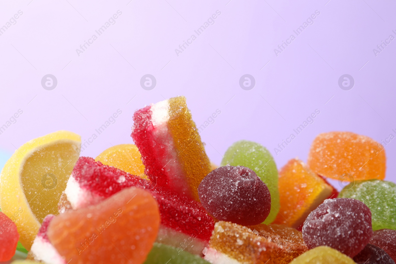 Photo of Pile of delicious bright jelly candies on violet background, closeup