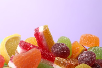 Photo of Pile of delicious bright jelly candies on violet background, closeup