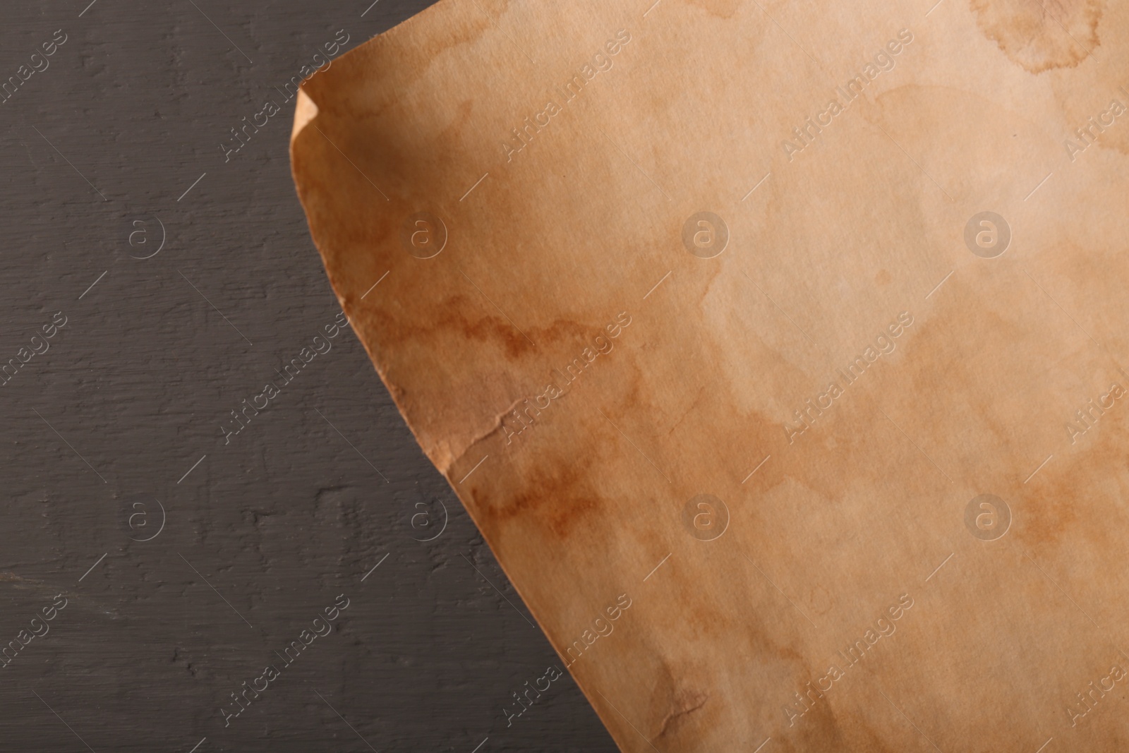 Photo of Sheet of old parchment paper on grey wooden table, top view. Space for text