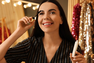 Photo of Beautiful young woman applying mascara in dressing room