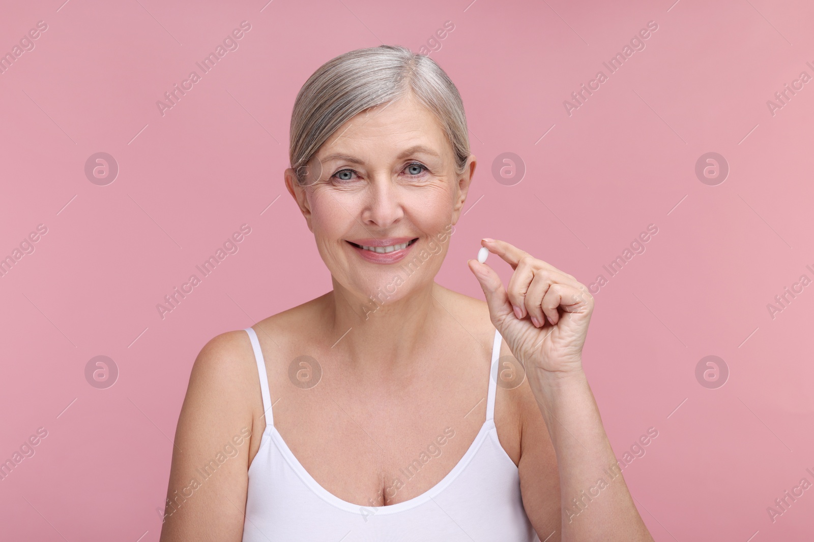 Photo of Beautiful woman with vitamin pill on pink background