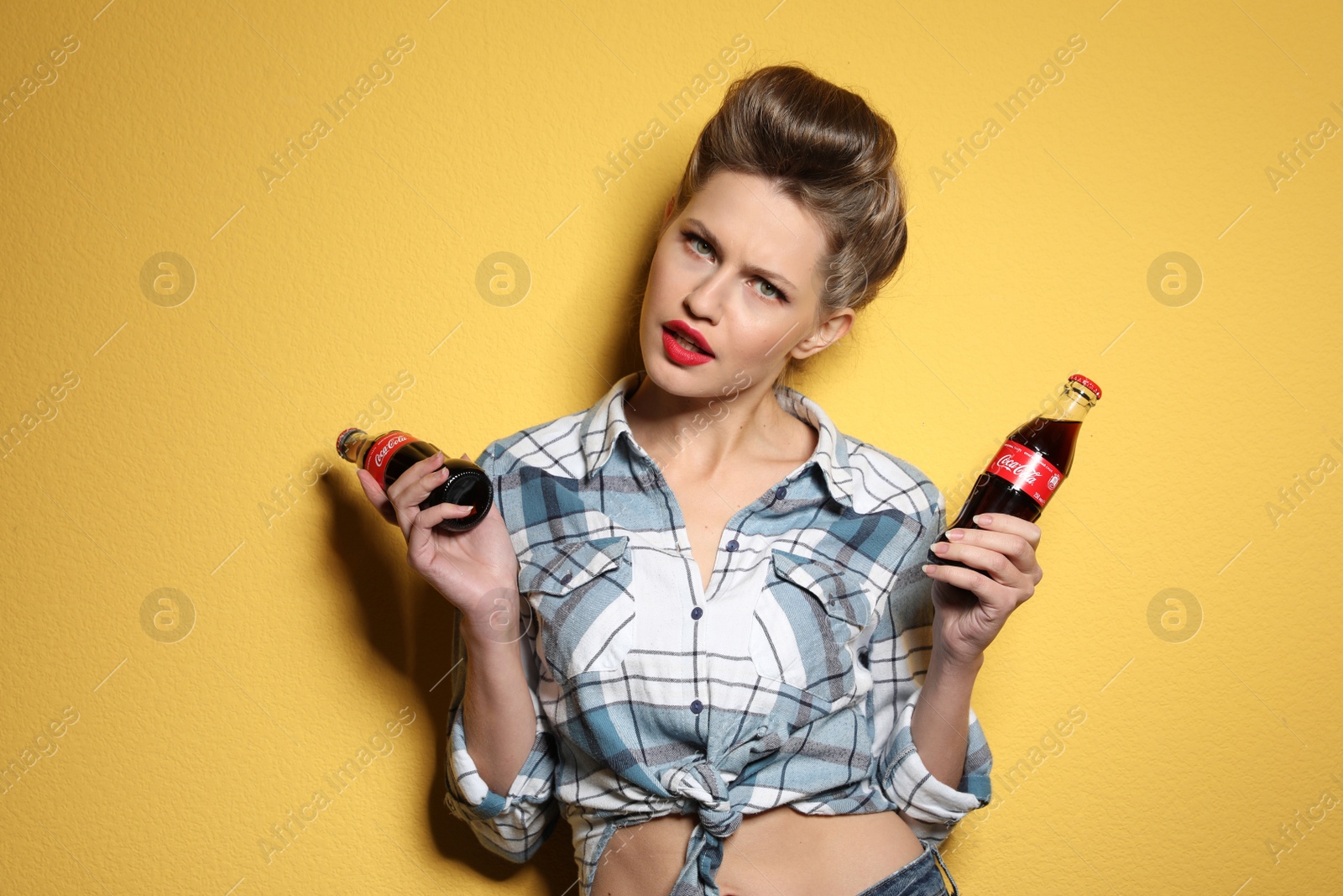 Photo of MYKOLAIV, UKRAINE - NOVEMBER 28, 2018: Young woman with bottles of Coca-Cola on color background