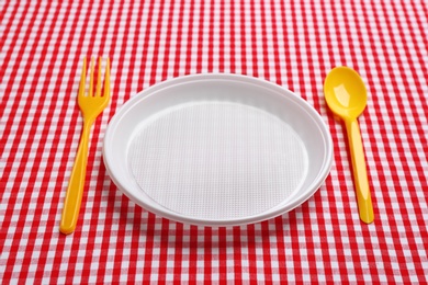 Photo of Table setting with plastic dishware on plaid fabric