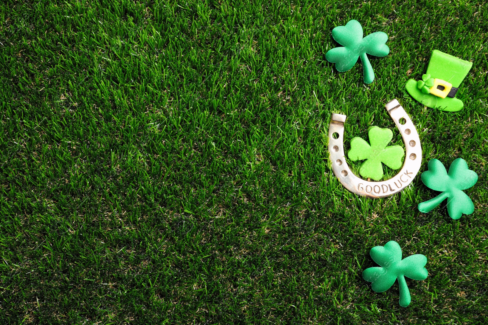 Photo of Flat lay composition with horseshoe on grass, space for text. St. Patrick's Day celebration