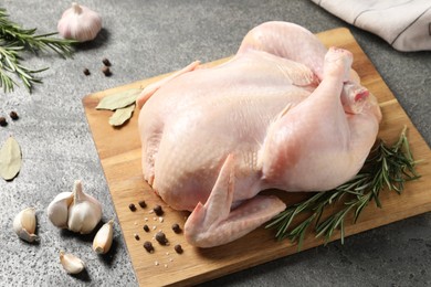 Photo of Fresh raw chicken with spices on grey textured table