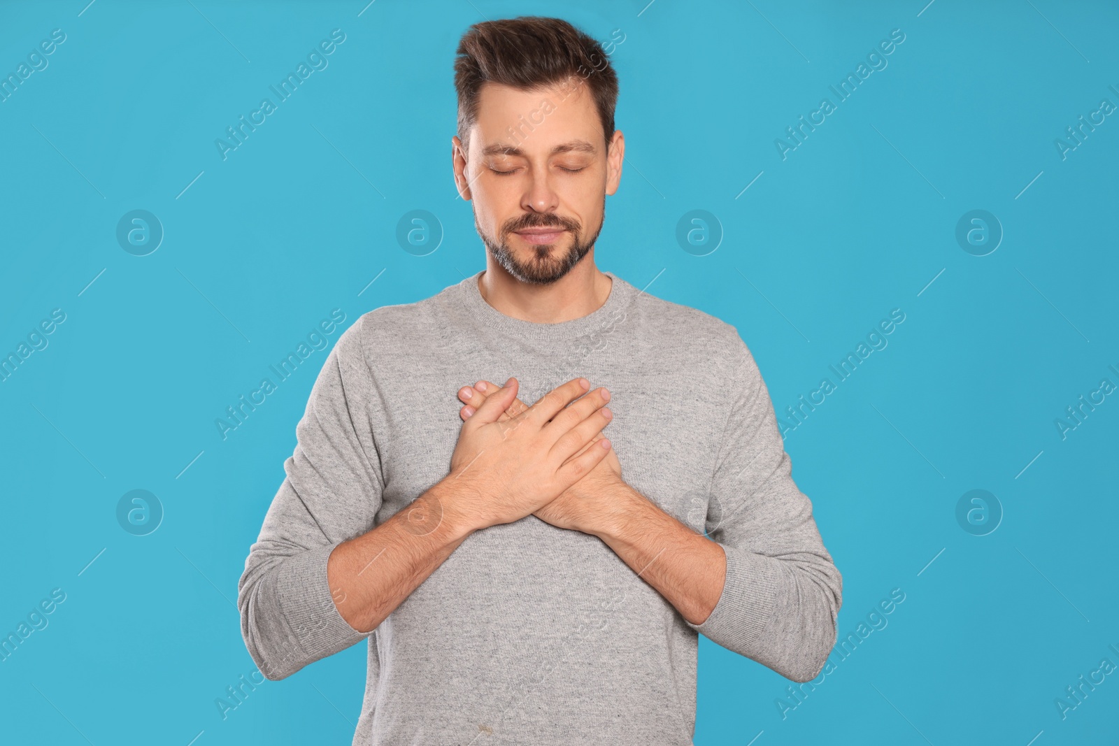 Photo of Man with clasped hands praying on turquoise background